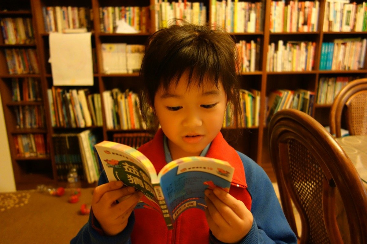 Niño leyendo un libro frente a estanterías de biblioteca