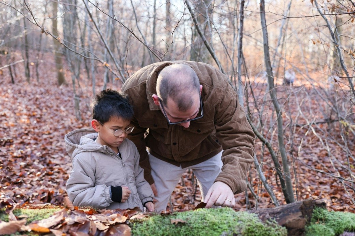 Adulto acompañando a un niño a observar la naturaleza en el bosque
