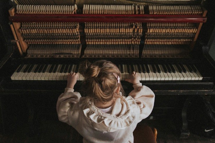 Niña explorando los sonidos de un piano en un espacio tranquilo