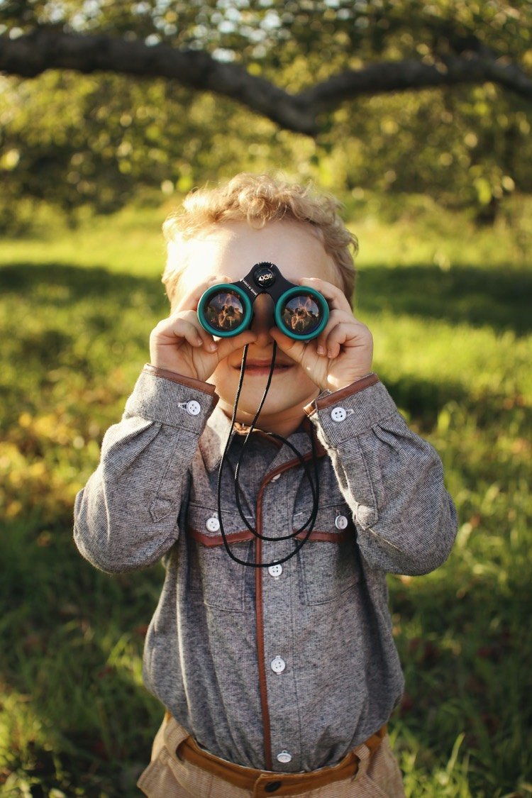 Niño mirando la naturaleza con binoculares al aire libre